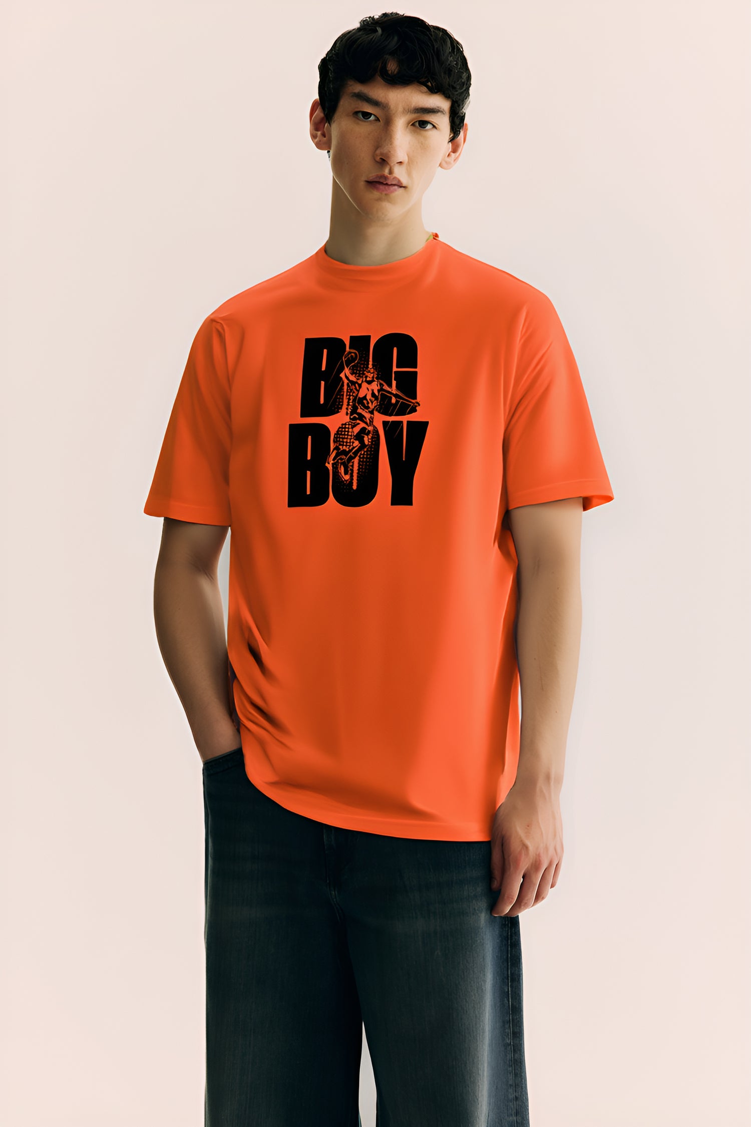 Person wearing an orange t-shirt with 'BIG BOY' text on a plain background